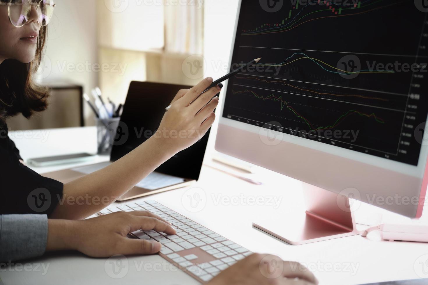 un experto en inversiones apunta con un lápiz al monitor de una tableta para analizar el mercado de valores y enseñarle cómo obtener ganancias. foto