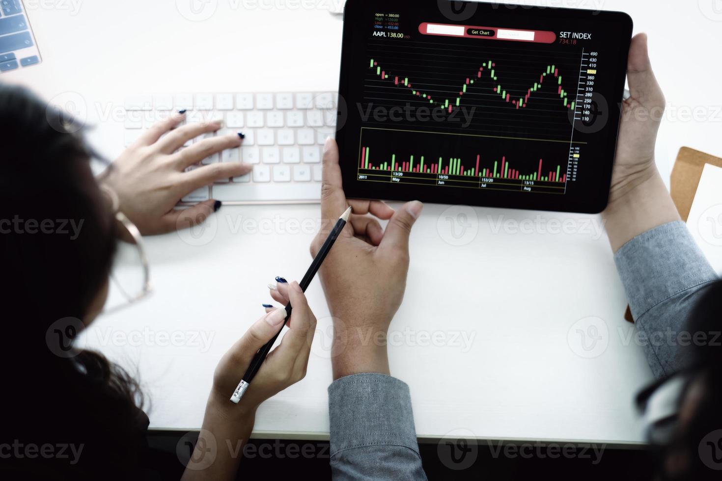 un experto en inversiones apunta con un lápiz al monitor de una tableta para analizar el mercado de valores y enseñarle cómo obtener ganancias. foto