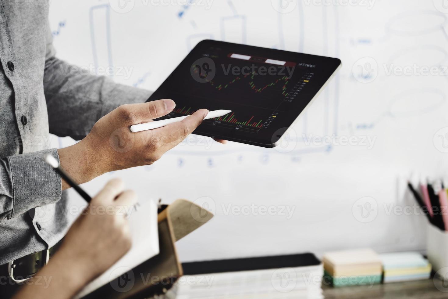 An investment expert points a pen at a tablet monitor to analyze the stock market to teach you how to make a profit. photo