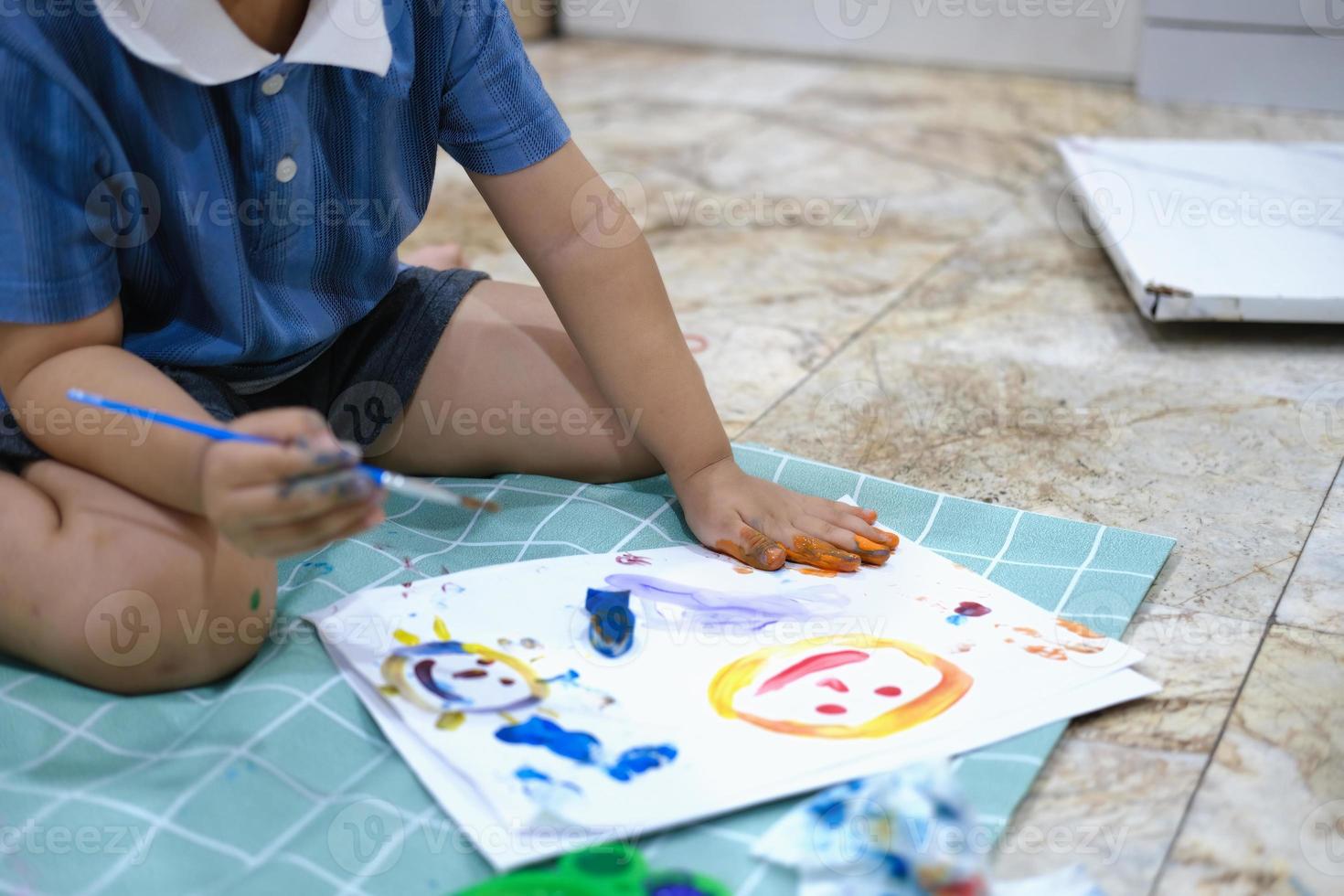 Concéntrese en las manos sobre el papel, el aprendizaje de la primera infancia mediante el uso de pinturas y pinceles para desarrollar la imaginación y mejorar las habilidades en la pizarra. foto