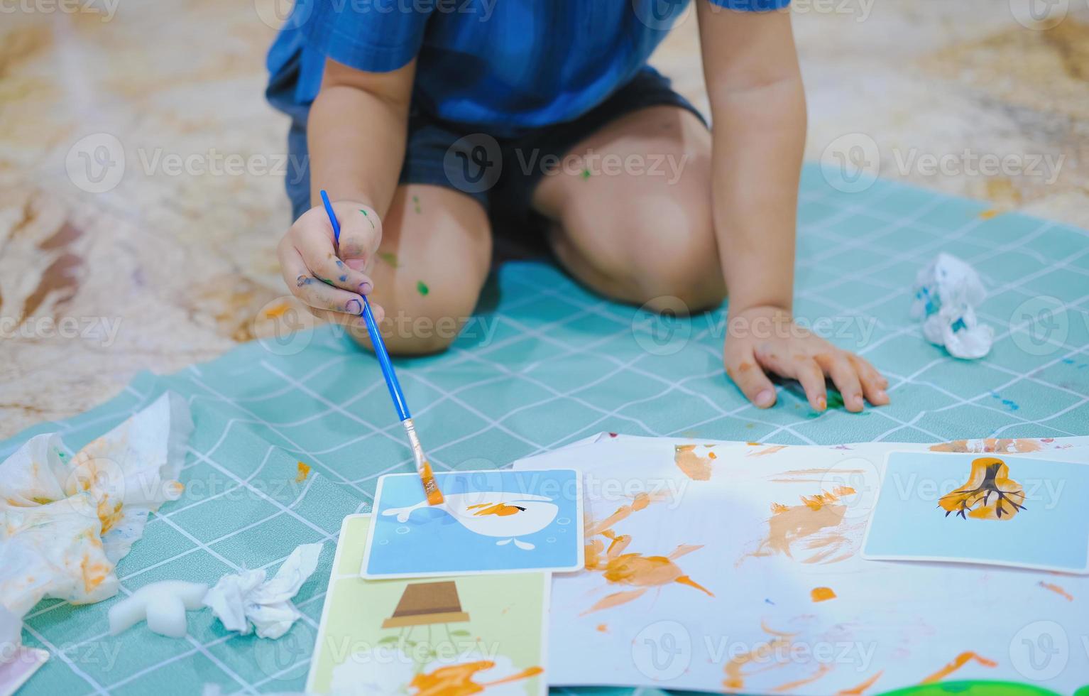 Children use paintbrushes to paint watercolors on paper to create their imagination and enhance their learning skills. photo