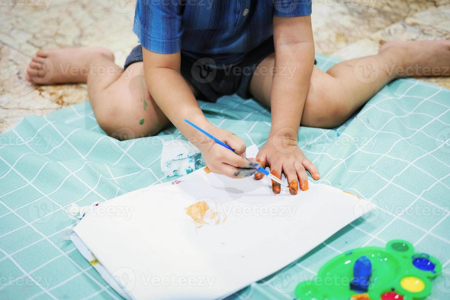 centrarse en sus manos sobre el papel. los niños usan pinceles para dibujar sus manos en el papel para desarrollar su imaginación y mejorar sus habilidades cognitivas. foto