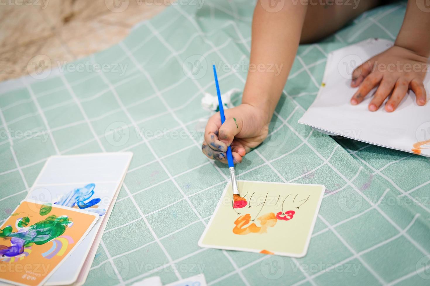 centrarse en las manos sobre el papel. los niños usan pinceles para pintar acuarelas en papel para crear su imaginación y mejorar sus habilidades de aprendizaje. foto