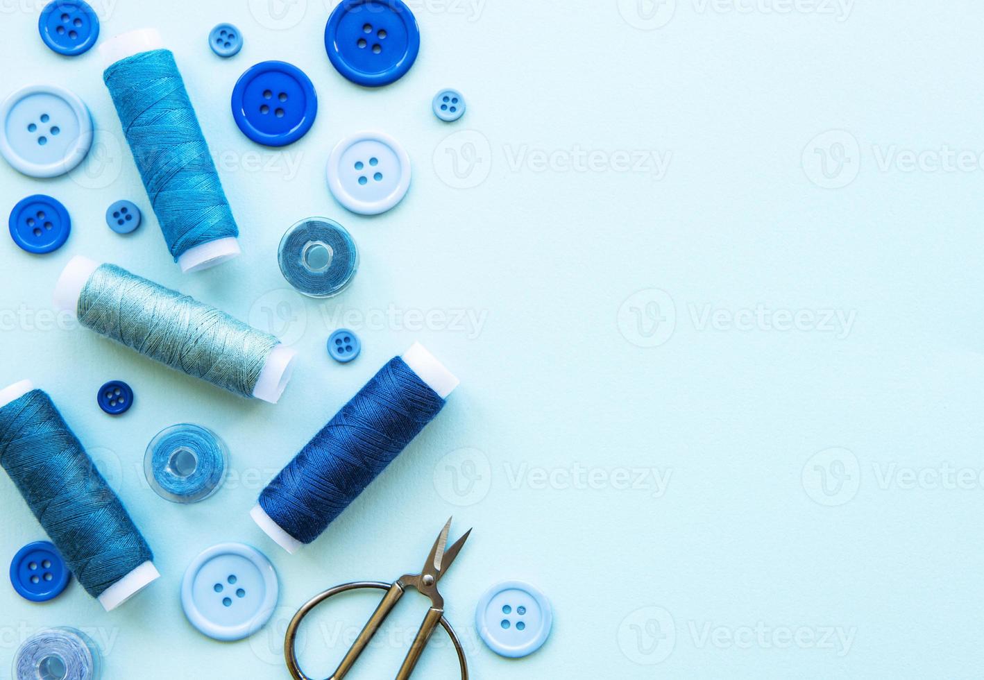 Spools of thread and buttons in blue tones on a blue background photo