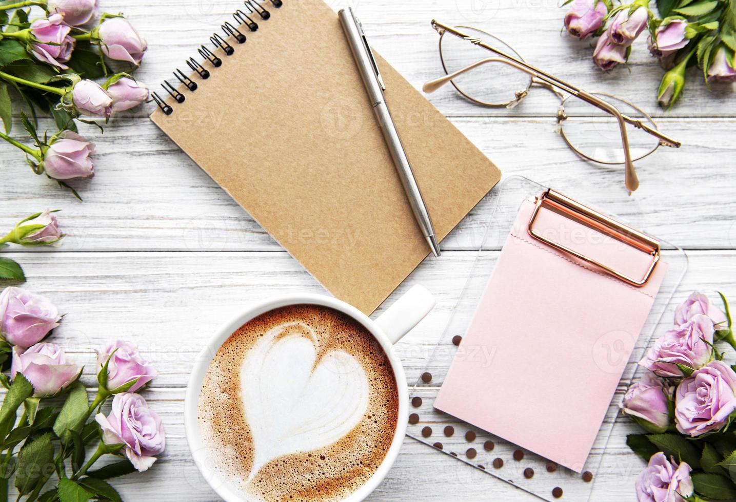 espacio de trabajo con diario, cuaderno, portapapeles, rosas sobre fondo blanco. foto