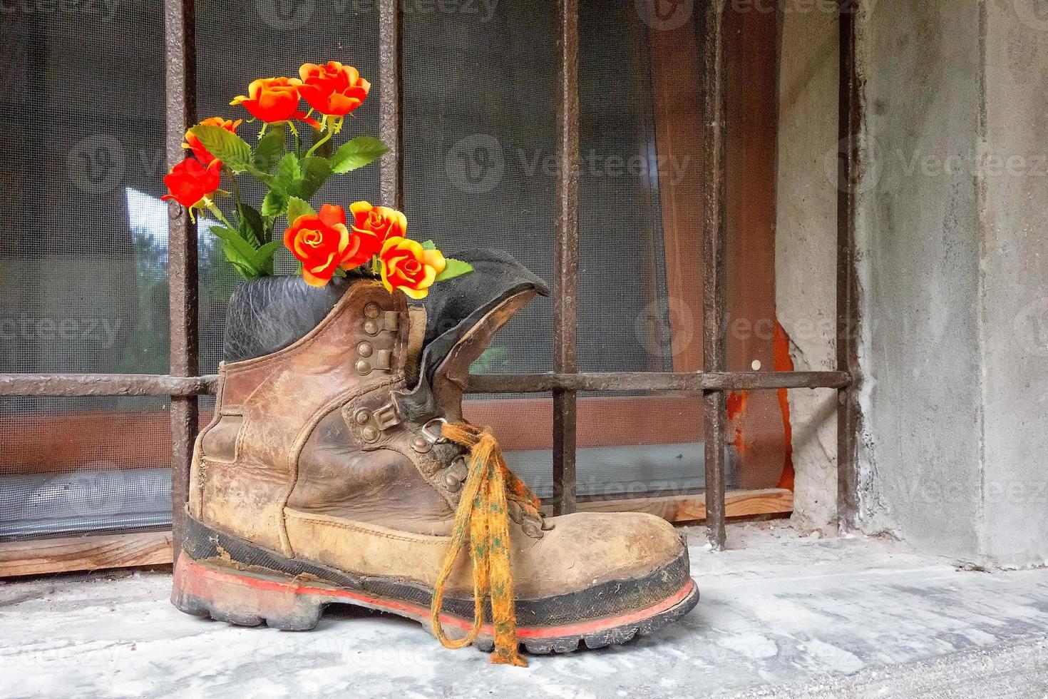 Bota de montaña vieja con flores en el interior en el balcón de la ventana foto