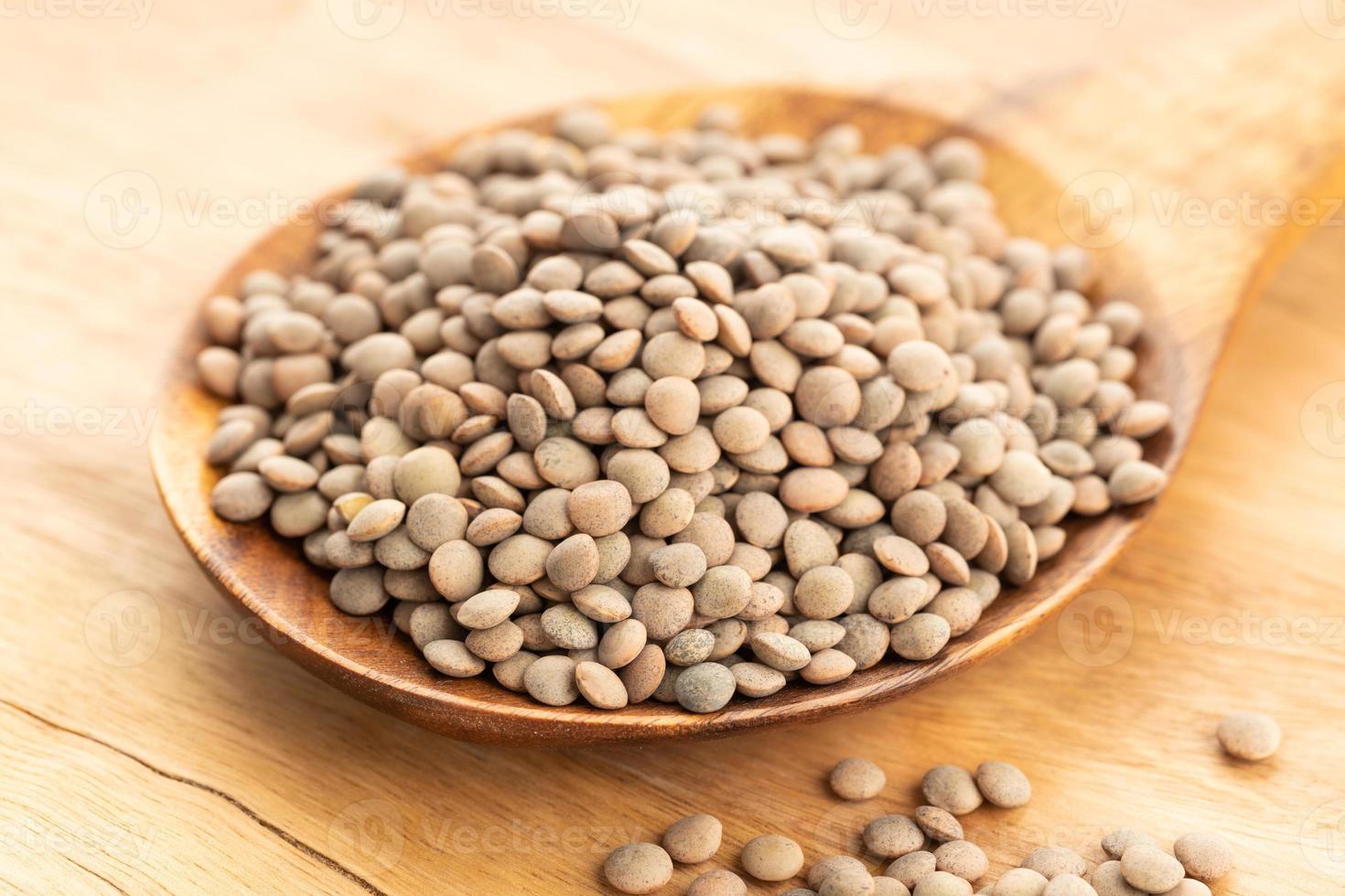 Lentil on wooden spoon on table. lens Variabilis photo