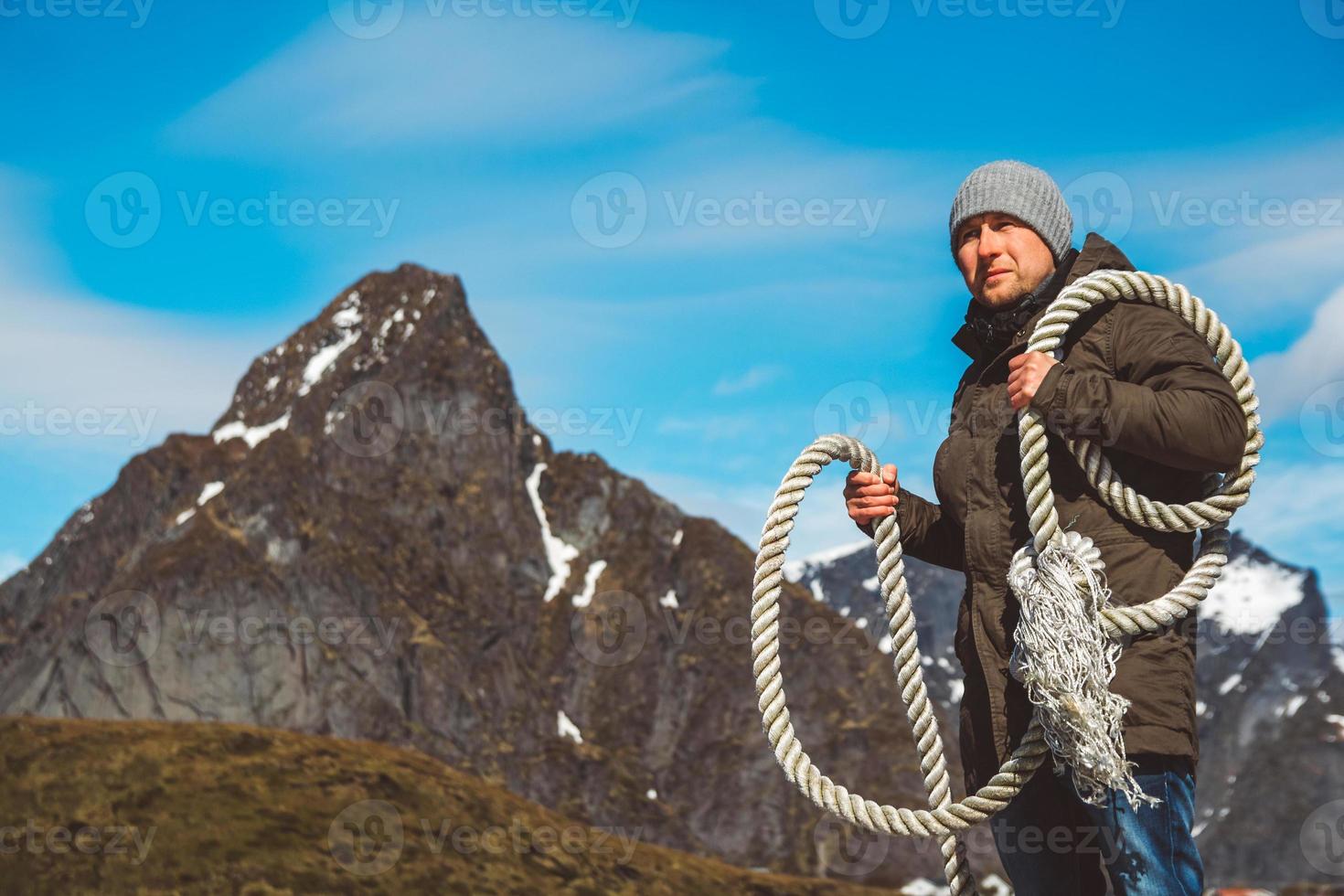 Man with a rope on his shoulder against background of the mountains and blue sky photo