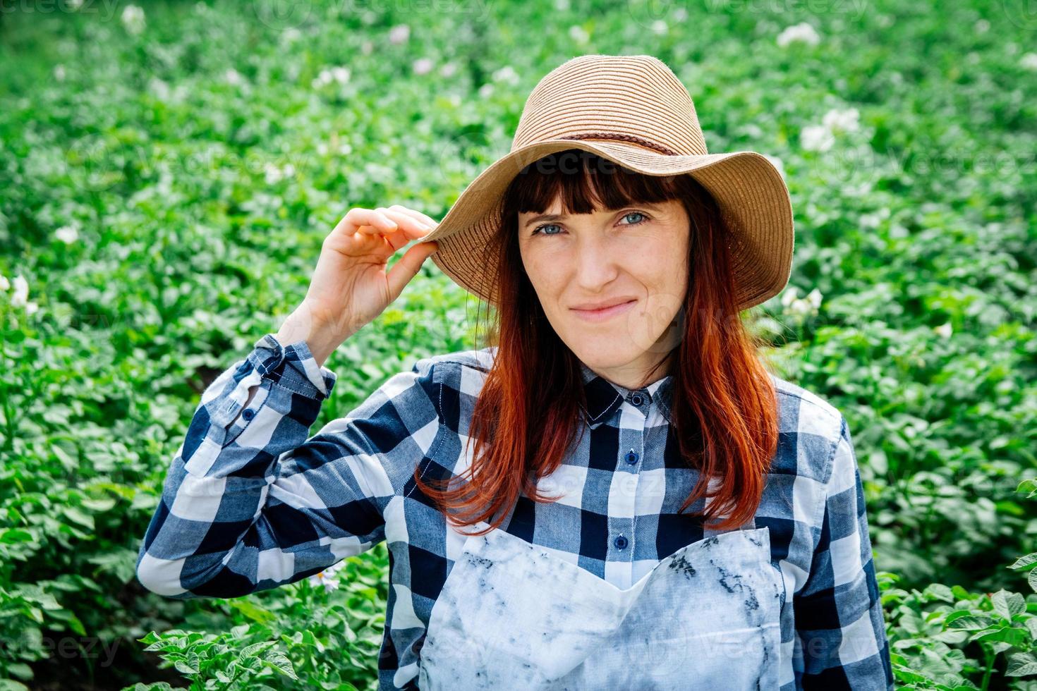 Retrato mujer campesina sonriendo a la cámara con un sombrero de paja en su huerto foto