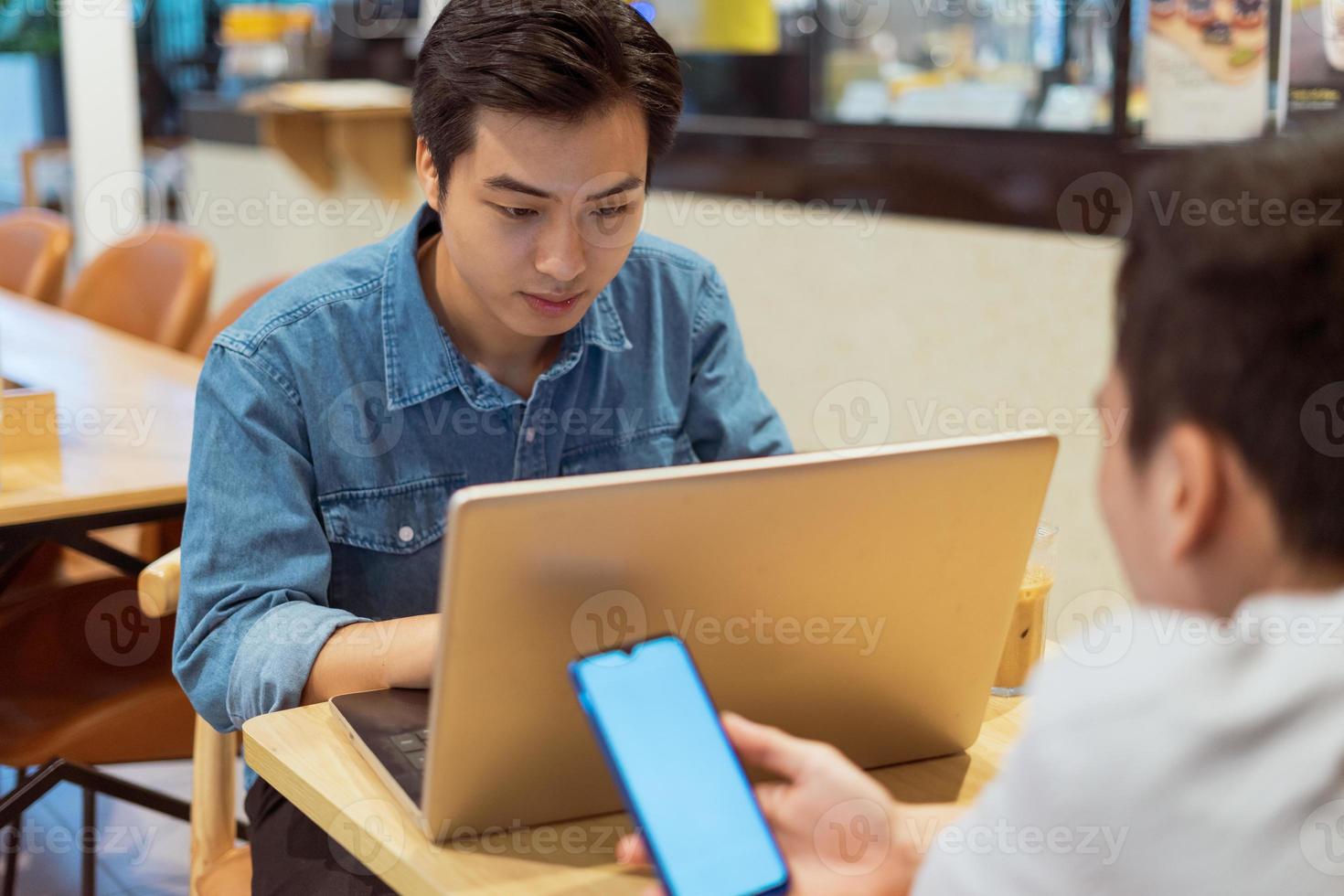 Hombre asiático que trabaja con su colega, en una cafetería. foto