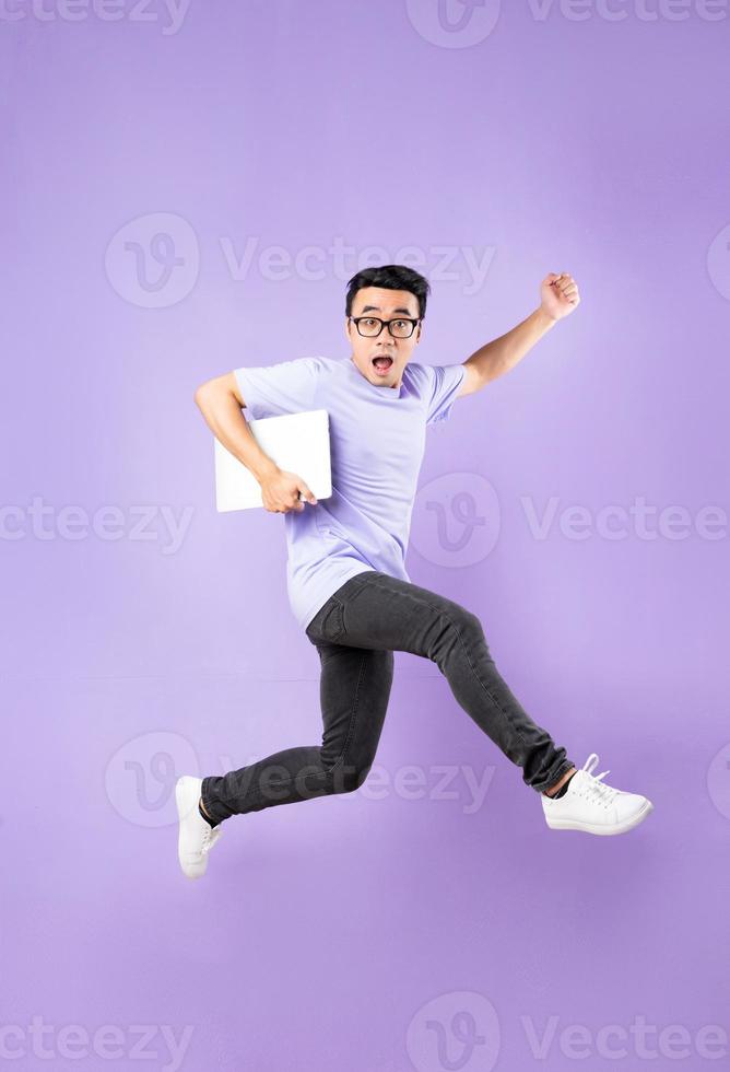 Portrait of a jumping asian man, isolated on purple background photo