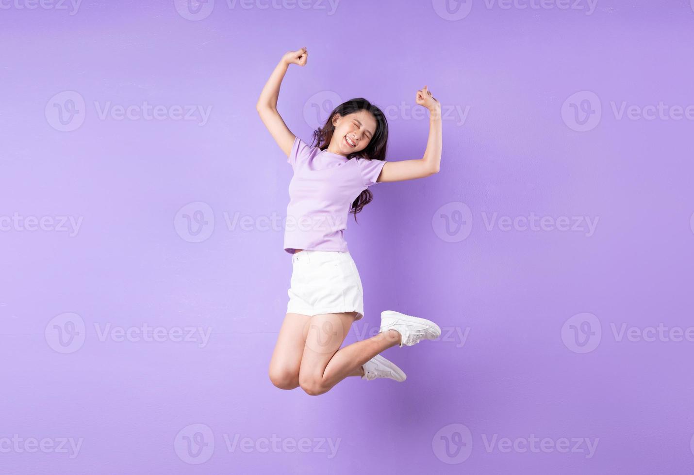 Young asian girl jumping up on purple background photo