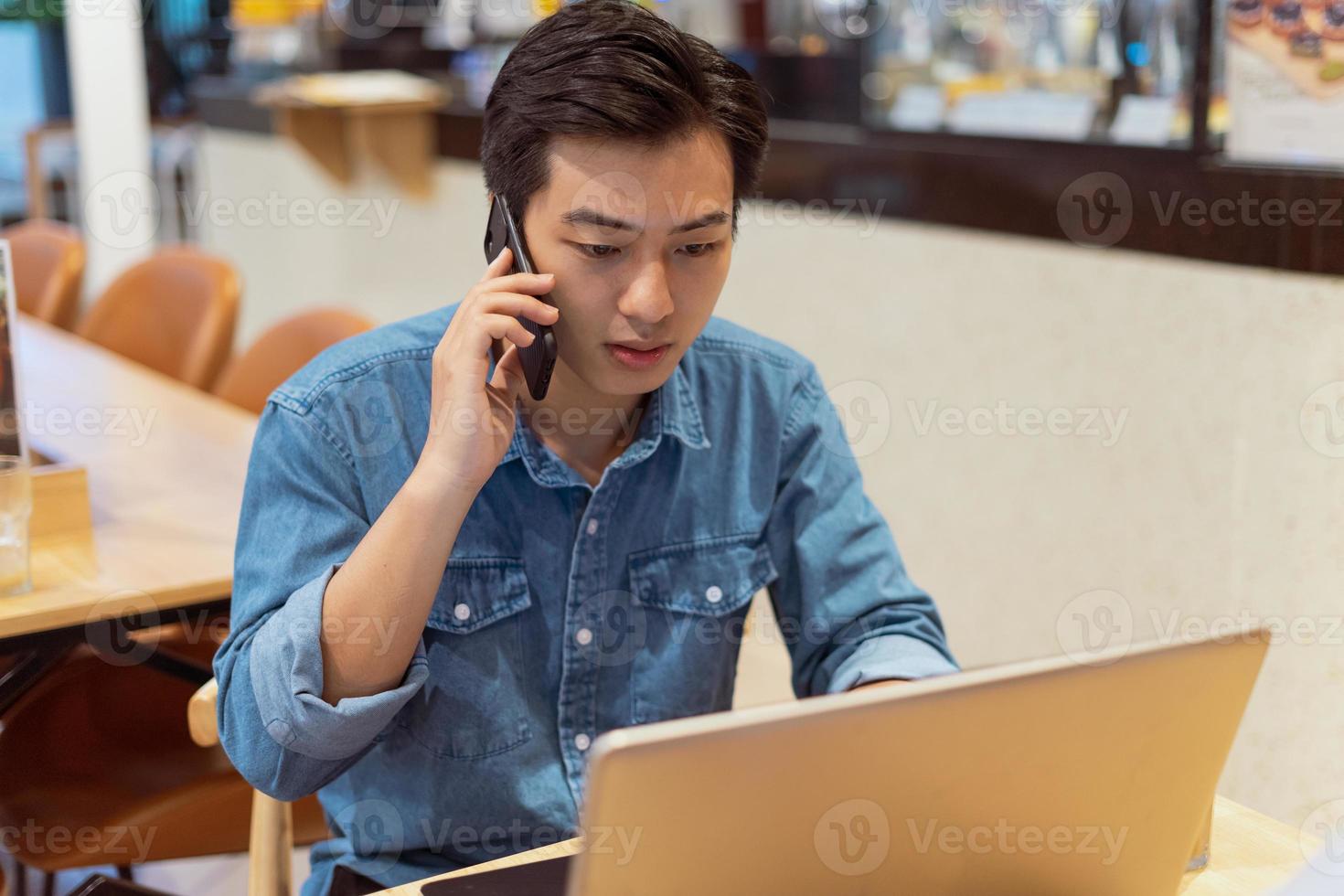 Hombre asiático pagando trabajando, en una cafetería. foto