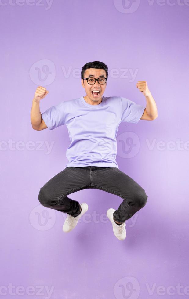 Portrait of a jumping asian man, isolated on purple background photo