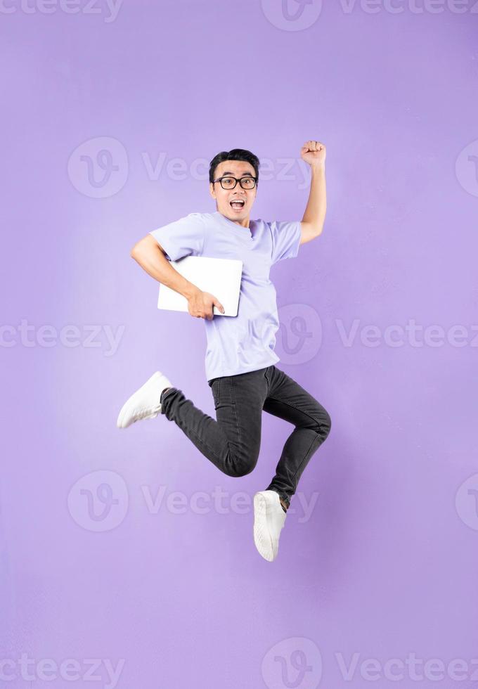 Retrato de un hombre asiático saltando, aislado sobre fondo púrpura foto