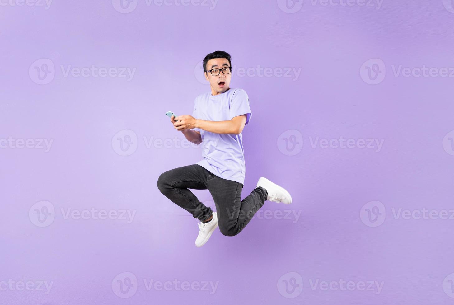 Retrato de un hombre asiático saltando, aislado sobre fondo púrpura foto