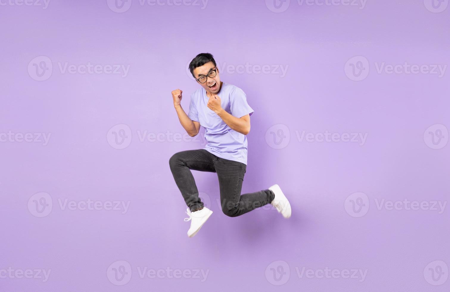 Retrato de un hombre asiático saltando, aislado sobre fondo púrpura foto