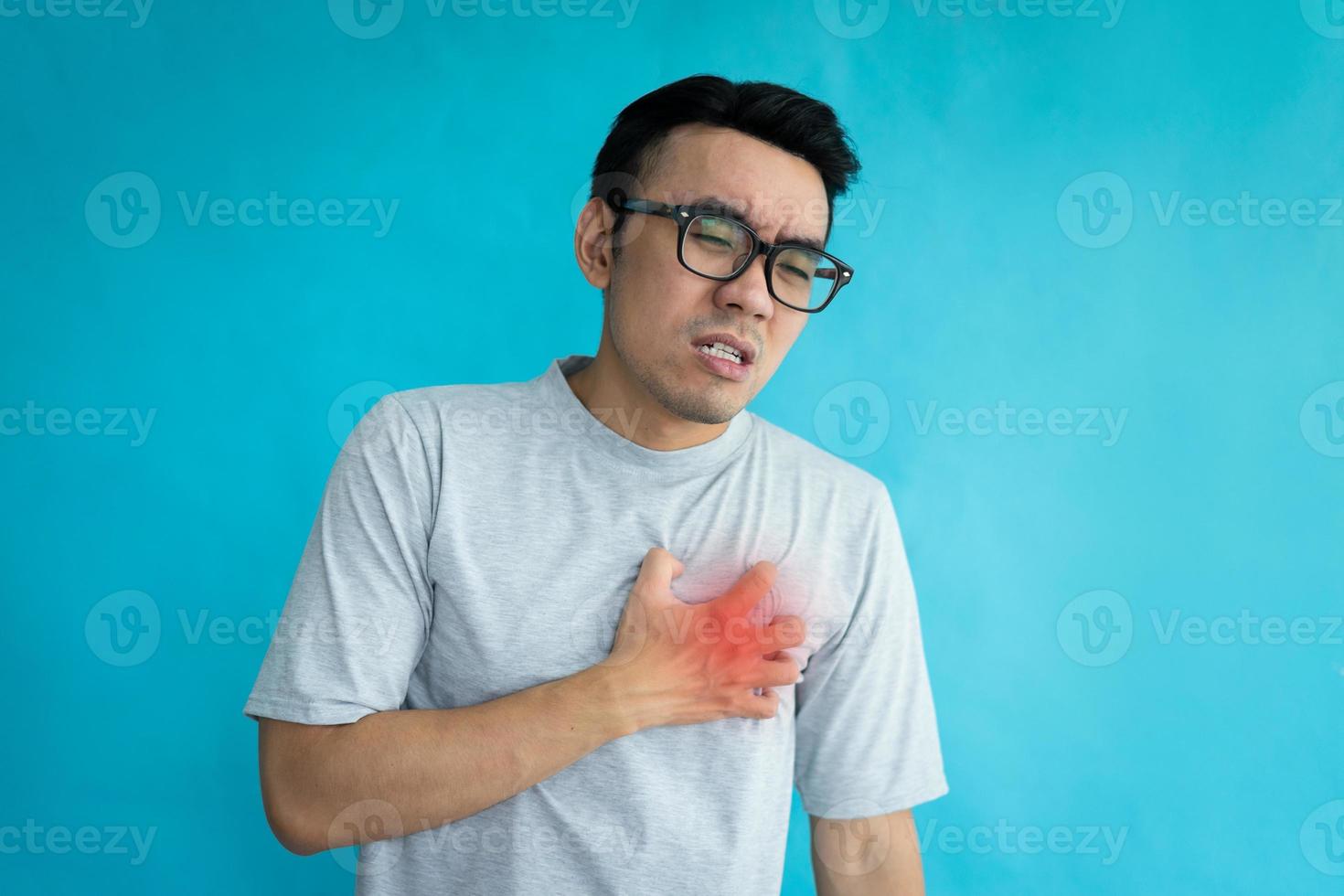 Retrato del hombre que tiene un ataque al corazón aislado sobre fondo azul. foto