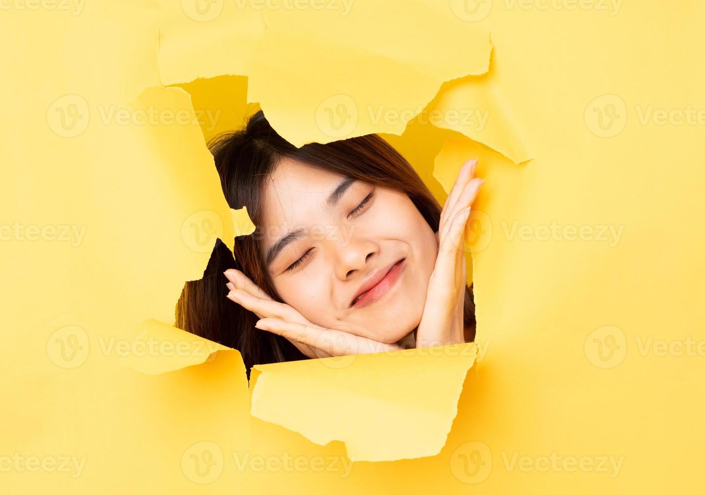 Young Asian woman poked her head through the torn paper photo