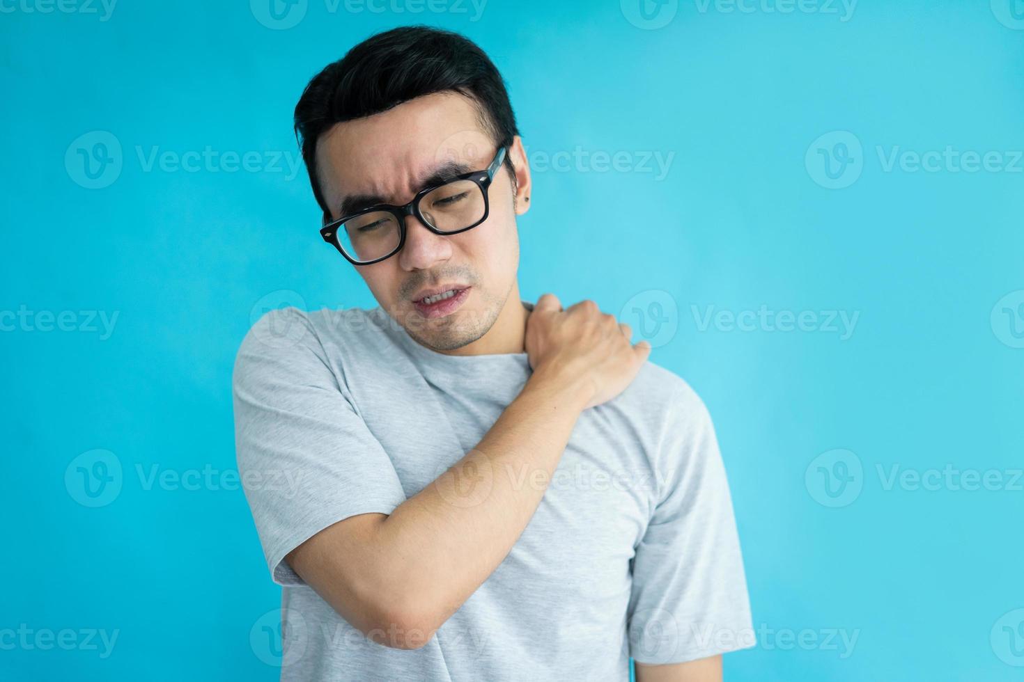 portrait of man with shoulder pain, isolated on blue background photo