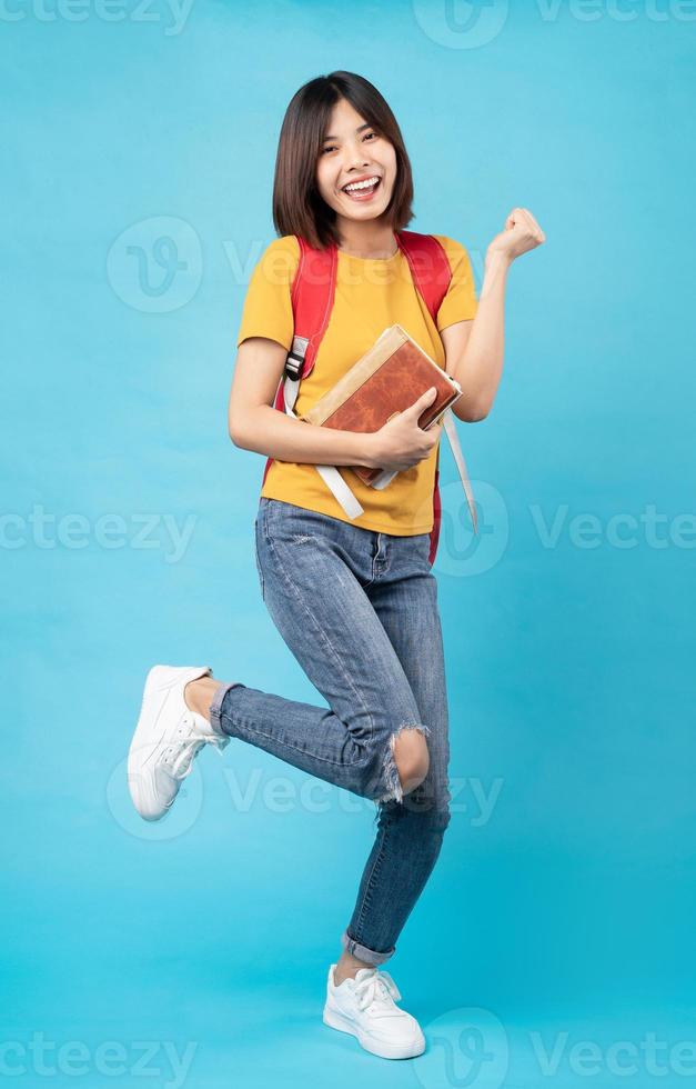 Portrait of young female student, isolated on blue background photo