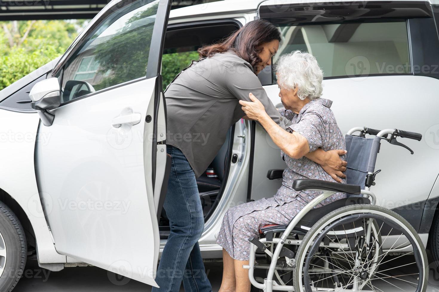 Help and support asian senior or elderly old lady woman patient sitting on wheelchair prepare get to her car, healthy strong medical concept. photo