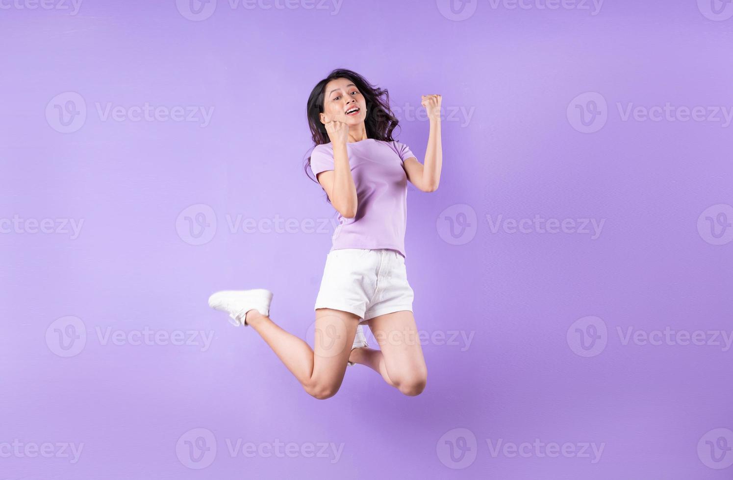 Young asian girl jumping up on purple background photo