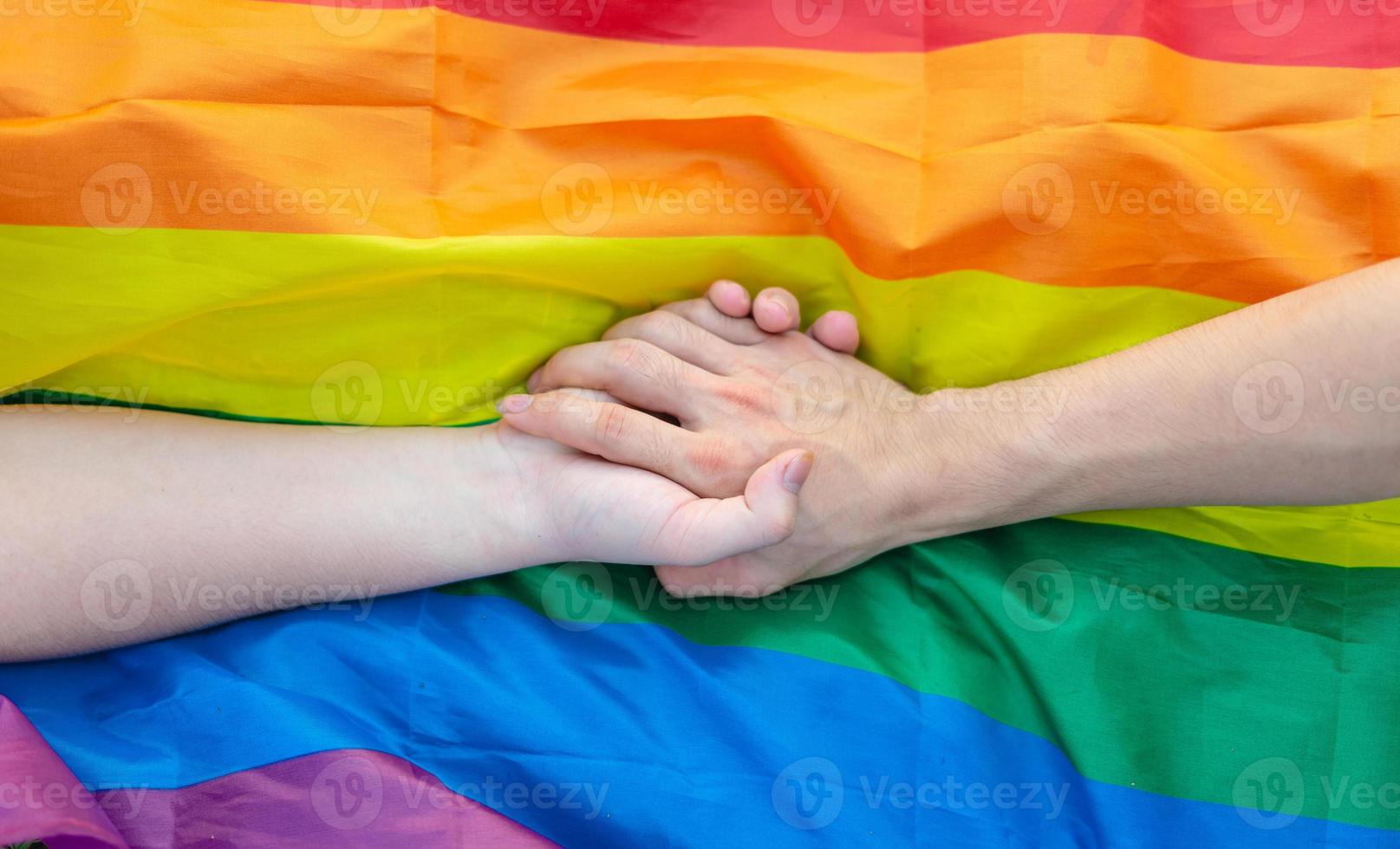 image of gay couple holding hands on lgbt flag photo