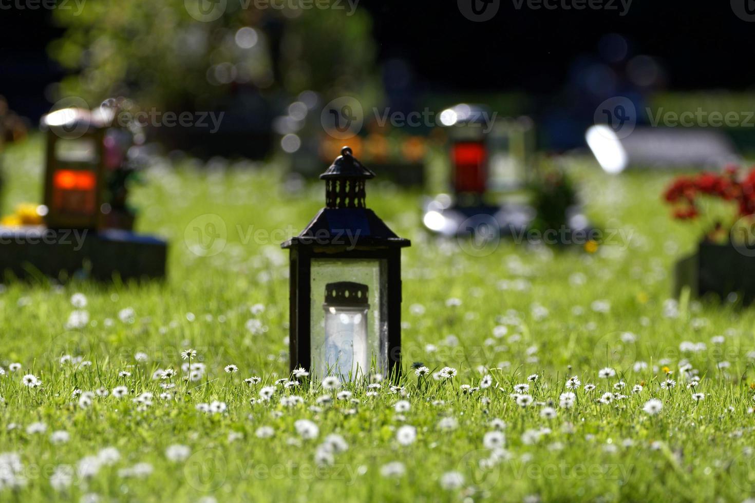 graves with grave lanterns in a flowering spring meadow photo