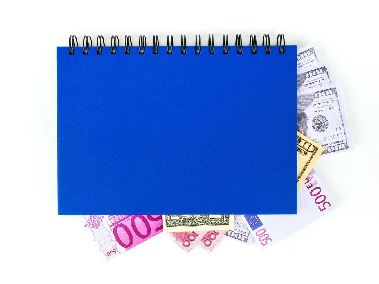 Libro azul con billetes internacionales anidados, aislado sobre fondo blanco. alijo de concepto de dinero, ideas de negocio foto