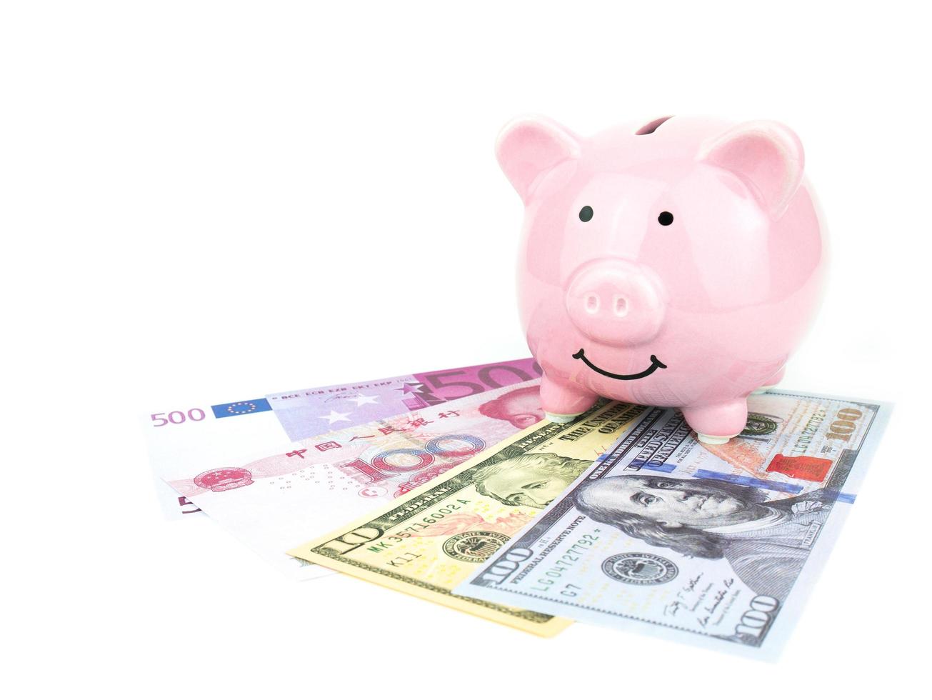 Pink piggy bank on dollars, chinese, euro banknote isolated on white background, saving concept photo