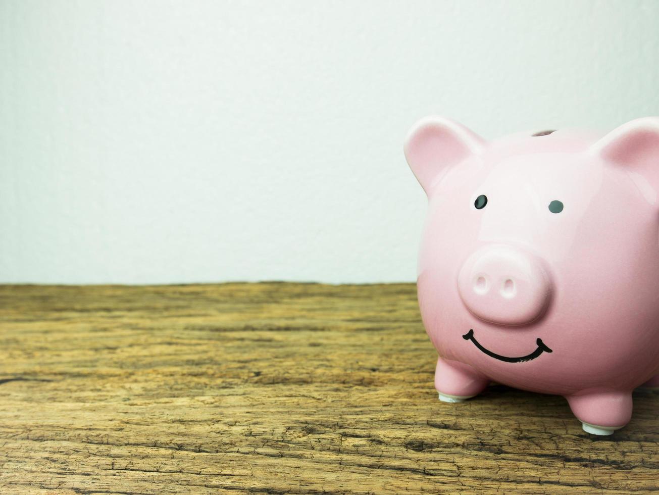 Pink piggy bank on wooden background photo