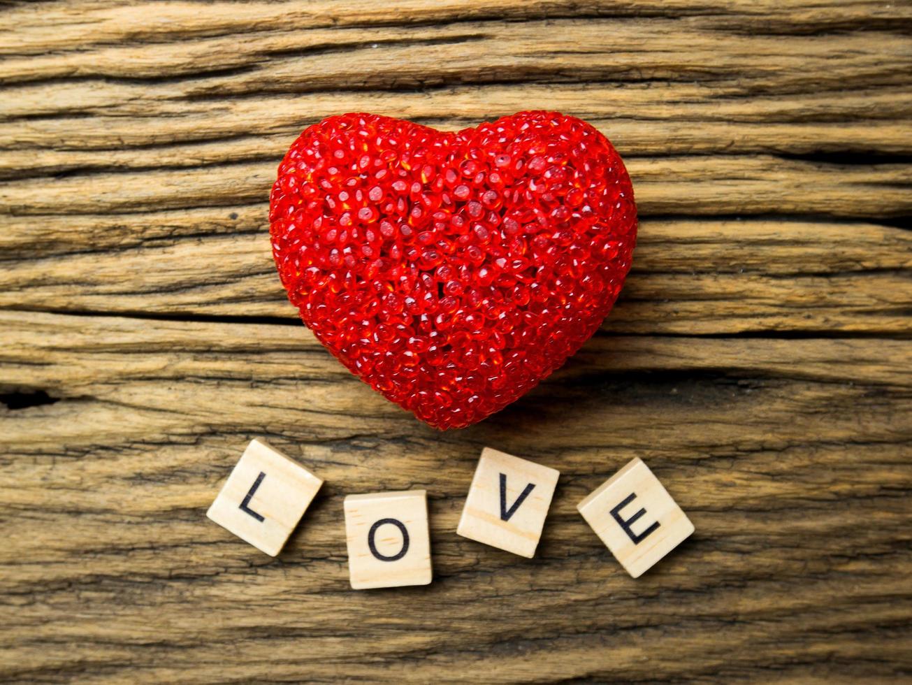 Vista superior del corazón rojo sobre fondo negro de madera, palabra de amor en cubo de madera, día de San Valentín foto