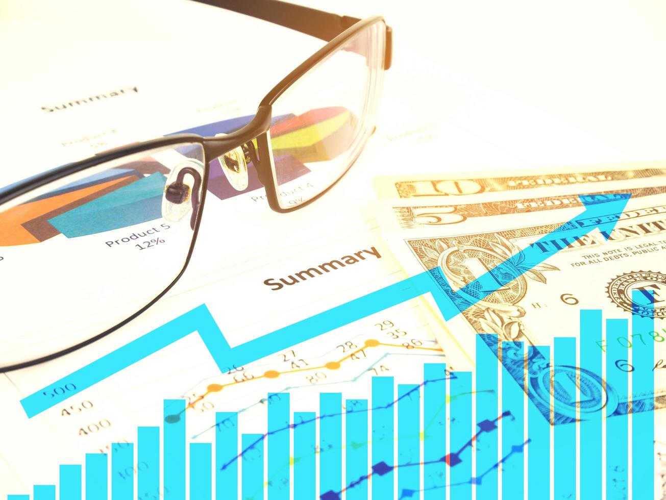 Gráfico de negocios cerca de dólares por gafas desenfocadas, concepto financiero foto