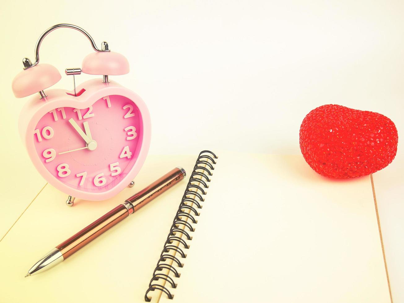 Cuaderno despertador y bolígrafo con corazón rojo, filtro vintage foto