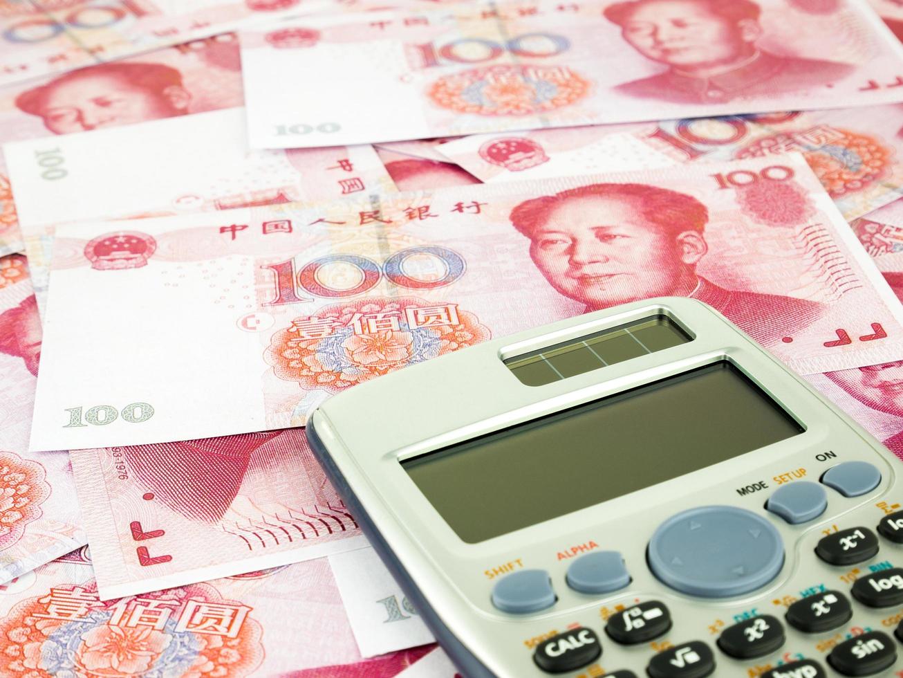 Es un montón de billetes de cien yuanes apilados como fondo con calculadora, monedas de yuanes chinos foto