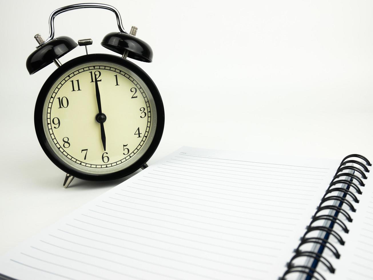 Blank notebook with alarm clock and on white background photo