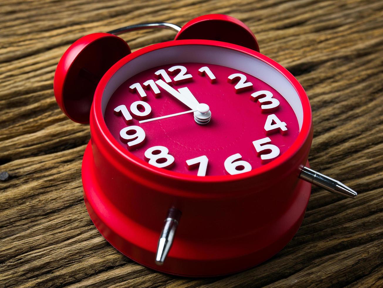 Red alarm clock on wooden background photo