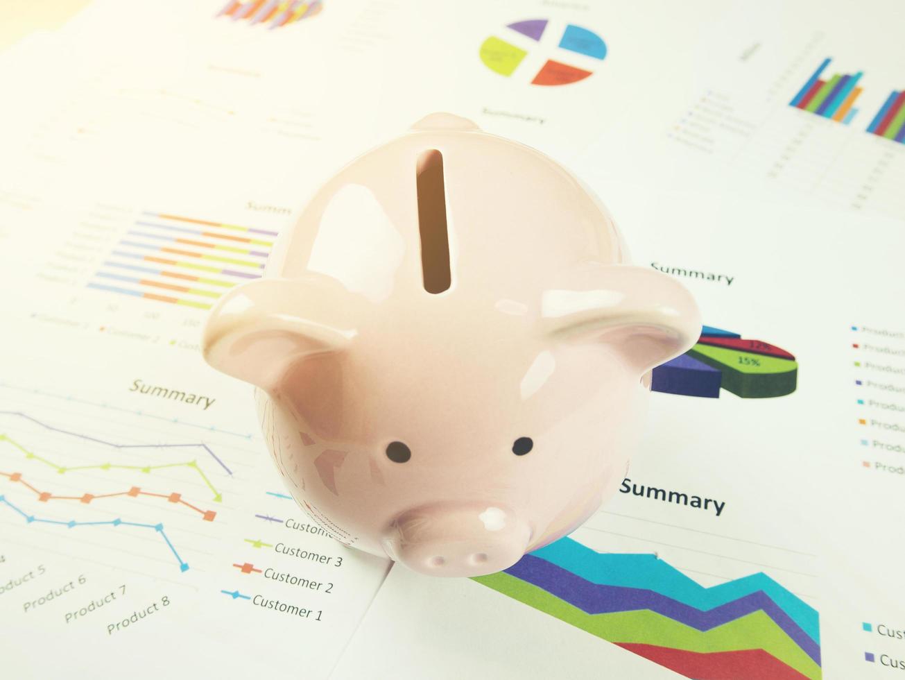 Gráfico de informe comercial y análisis de gráfico financiero con hucha rosa sobre la mesa, concepto de economía foto