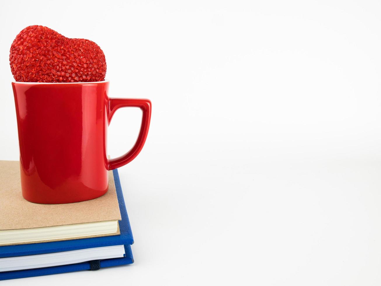 Taza con corazones rojos y libro aislado sobre fondo blanco, decoraciones de San Valentín foto