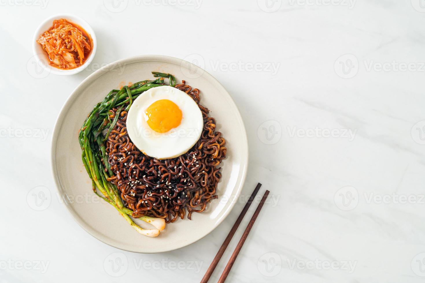 dried Korean spicy black sauce instant noodles with fried egg and kimchi photo