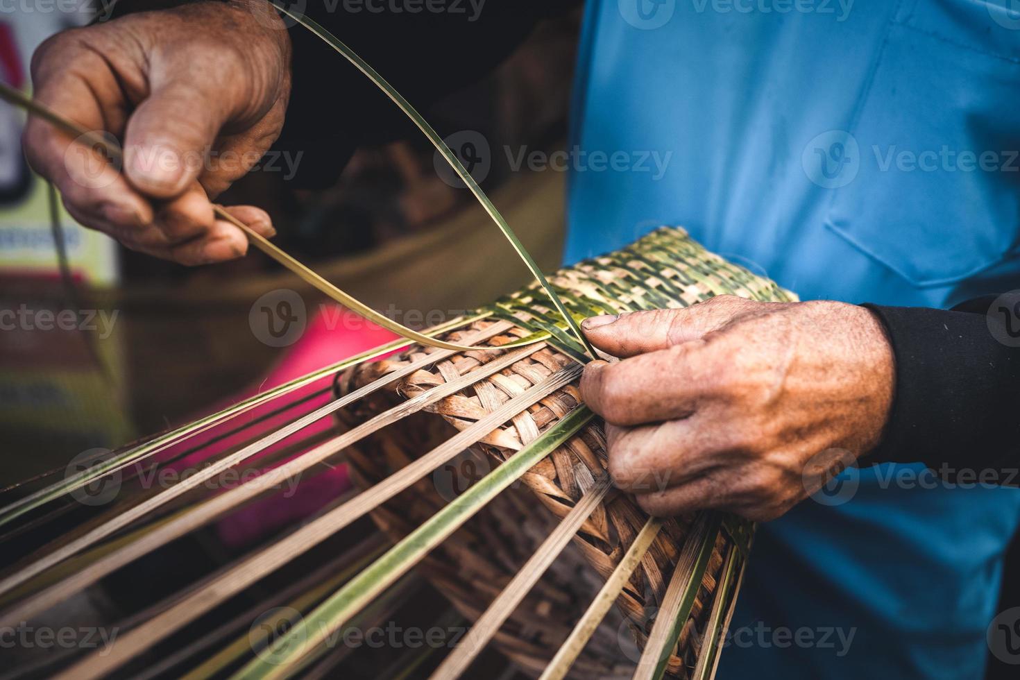 manos tejiendo cestas de bambú en casa foto