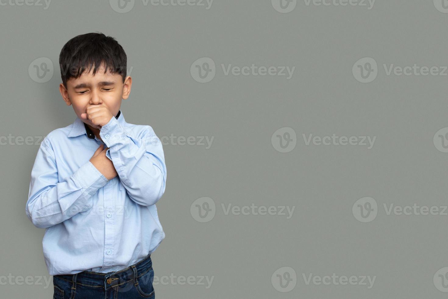 Cute little boy is coughing, on gray background photo