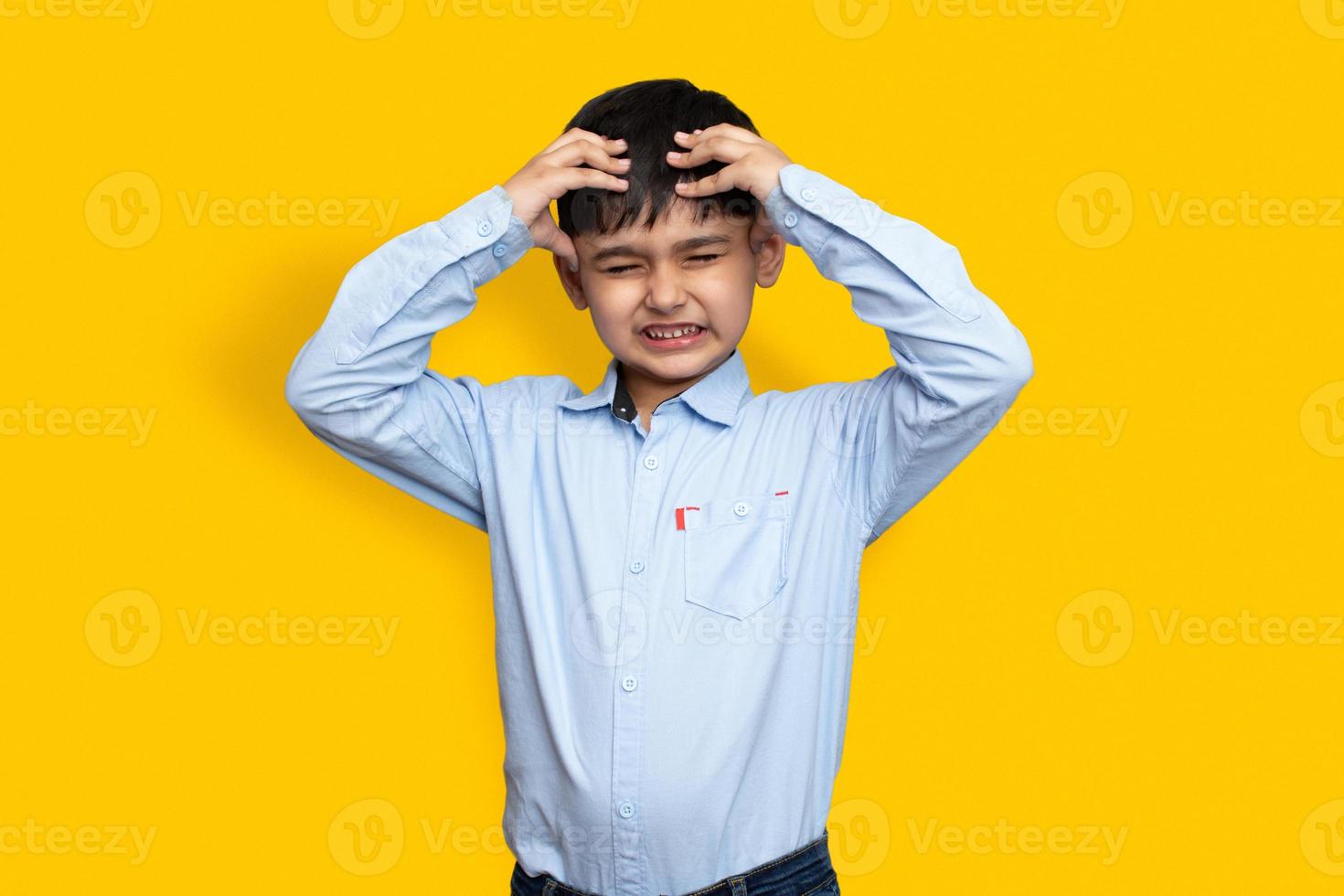 Sad and aggressive Little sick boy holding his head with his hand on plane isolated background with copy space photo