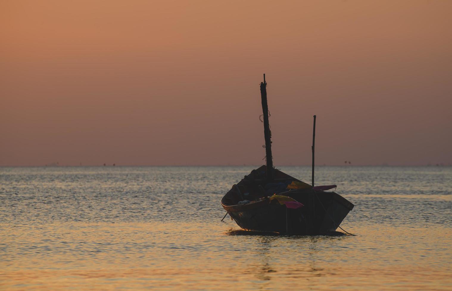 Barco de madera de pesca con luz tenue del cielo al atardecer. foto