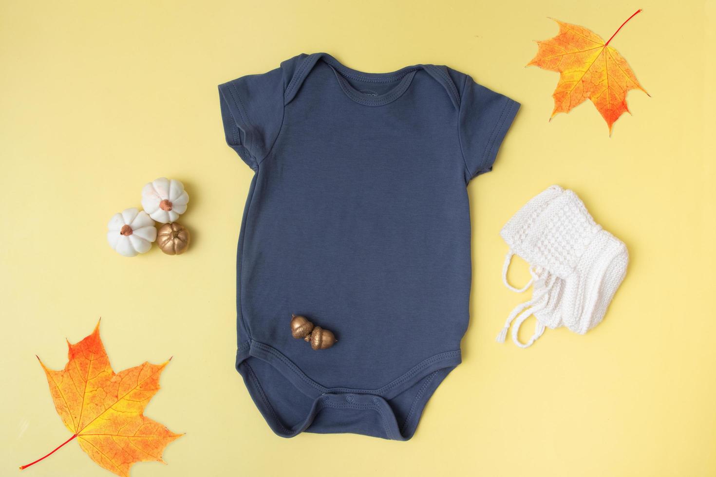 Baby clobodysuit mock-up with pumpkins on yellow background for your text or logo place in autumn season photo