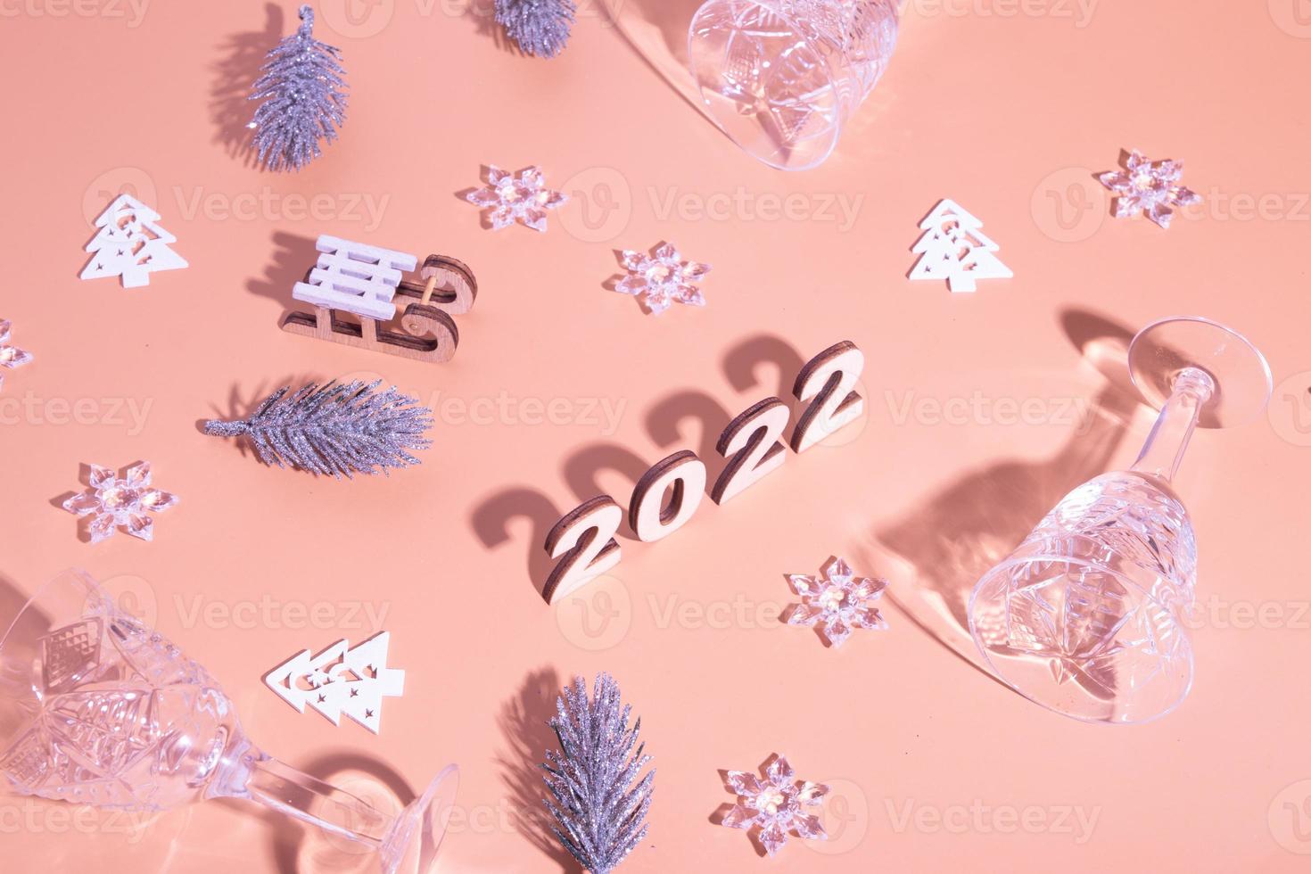 Festive new year flat lay with numbers 2022 and hard shadows with glasses and shiny decor photo