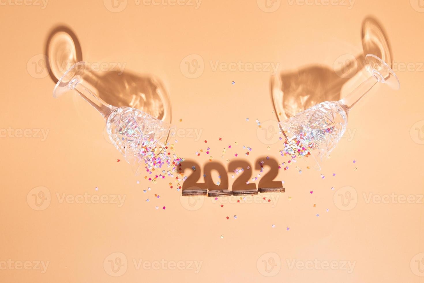 Festive new year flat lay with numbers 2022 and hard shadows with glasses and shiny decor photo