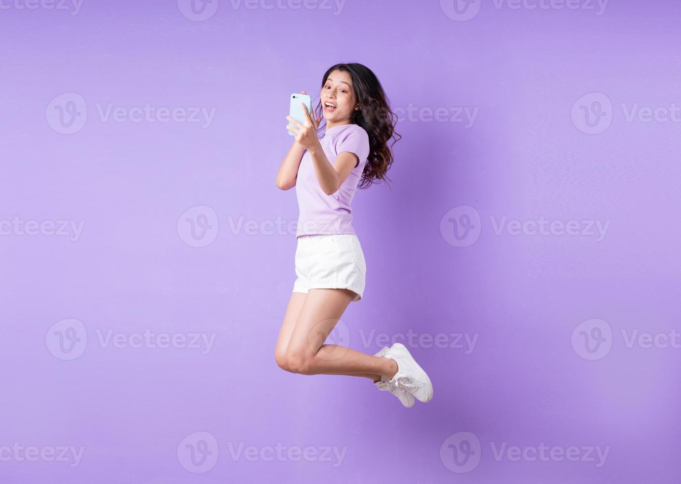 Young asian girl jumping up on purple background photo