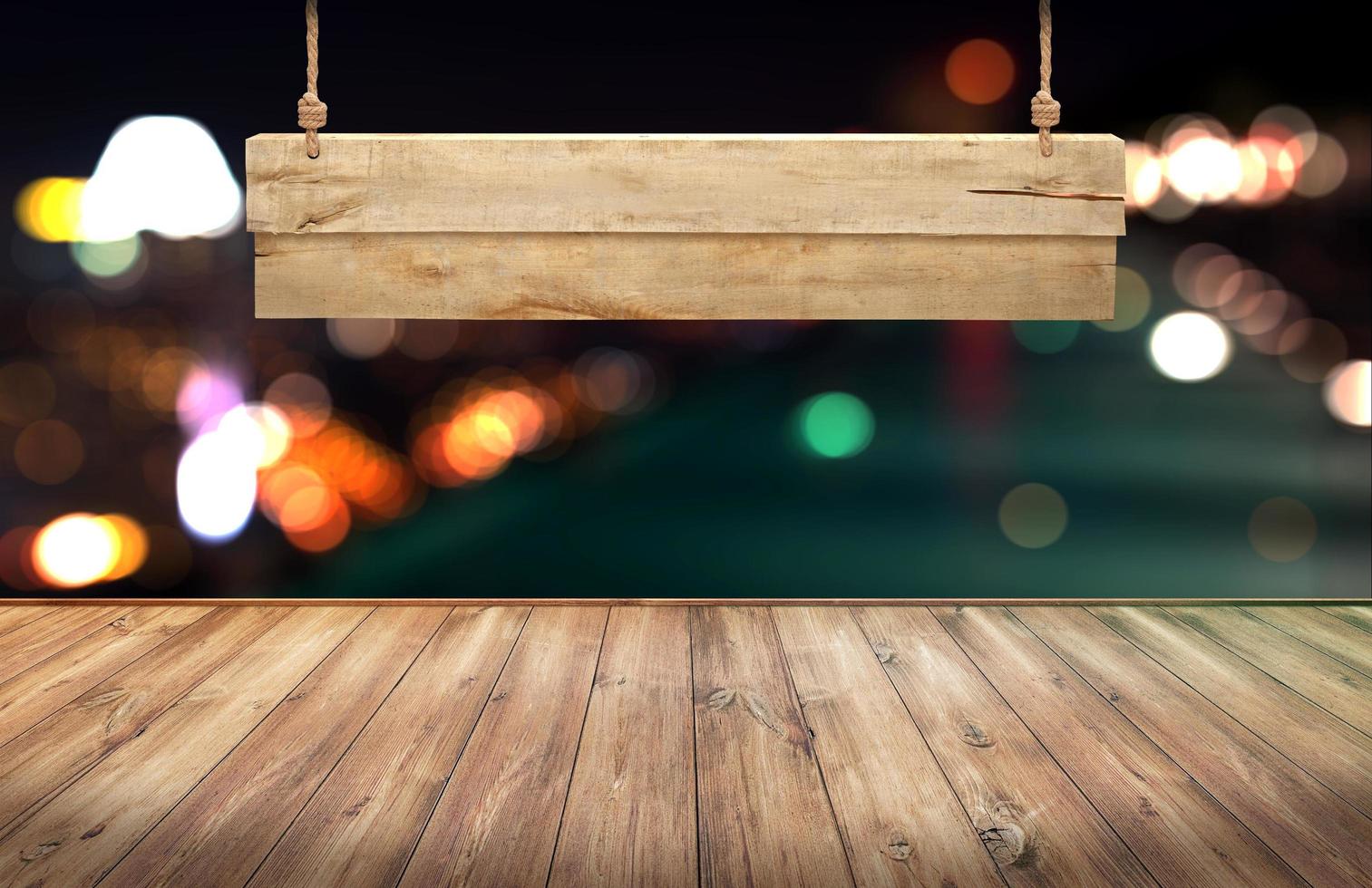 Wood table with hanging wooden sign on city lights night blurred background photo